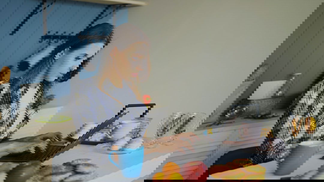 Lebensmittel online bestellen: Person mit Laptop in der Küche, Einkauf und Gutscheinrabatte digital planen