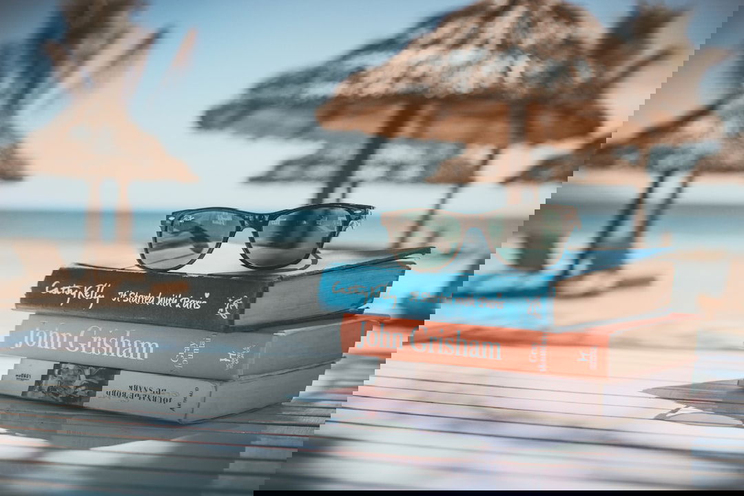 Urlaubsgutschein: Sonnenbrille auf Buch als Symbol für Reiseplanung und Angebote