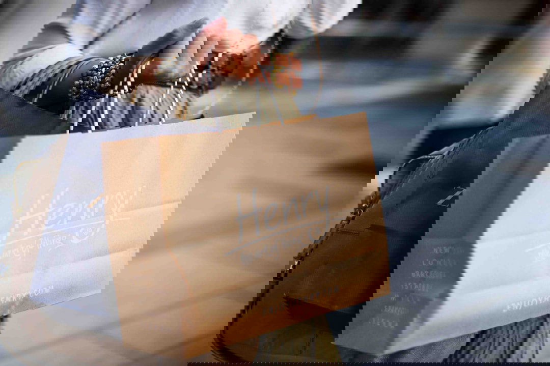 Person hält mehrere Papier-Einkaufstüten in der Hand