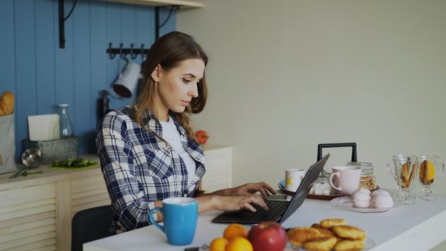 Lebensmittel online bestellen: Person mit Laptop in der Küche, Einkauf und Gutscheinrabatte digital planen
