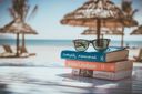 Urlaubsgutschein: Sonnenbrille auf Buch als Symbol für Reiseplanung und Angebote