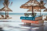 Urlaubsgutschein: Sonnenbrille auf Buch als Symbol für Reiseplanung und Angebote