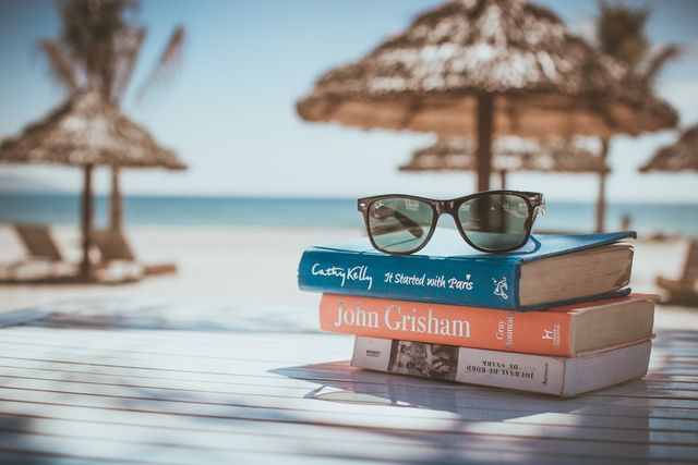 Urlaubsgutschein: Sonnenbrille auf Buch als Symbol für Reiseplanung und Angebote